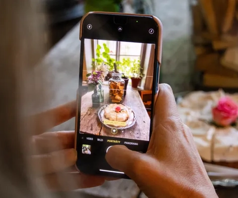 En person fotograferar ett bakverk med sin mobiltelefon.