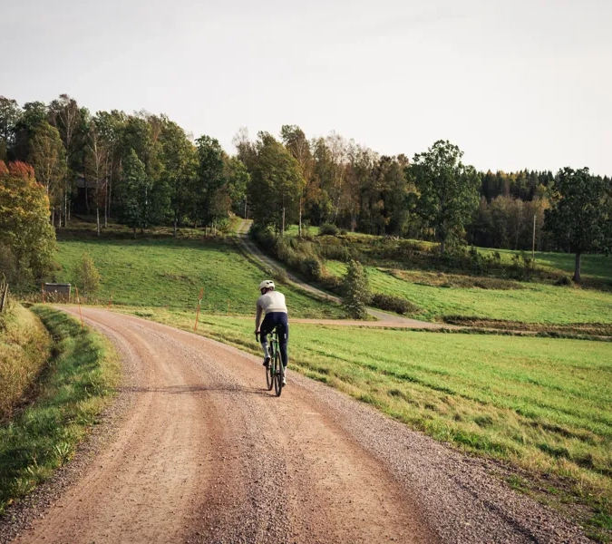 Cyklist på en grusväg i bruksmiljö.