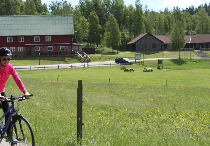 kvinna som cyklar framför gård