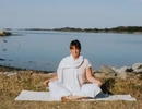 Människa som utövar yoga utomhus vid havet.