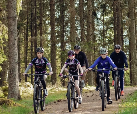 Eine Gruppe von Leuten, die auf Fahrrädern eine unbefestigte Straße hinunterfahren.