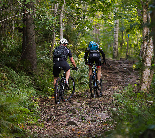 Två personer cyklar MTB uppför en brant backe.