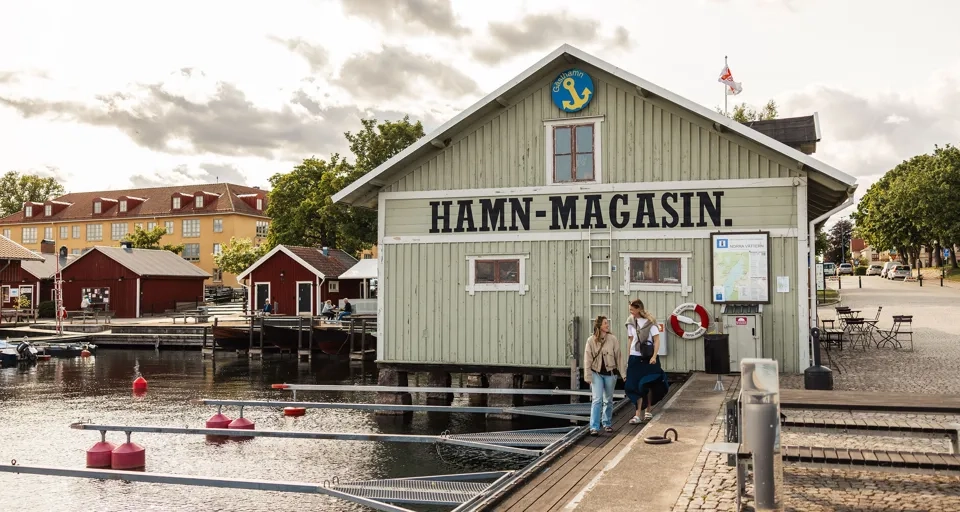 En grupp människor som står utanför en byggnad intill ett vattendrag.