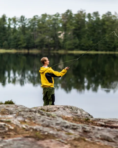 Ein Mann, der auf einem Felsen neben einem See steht.