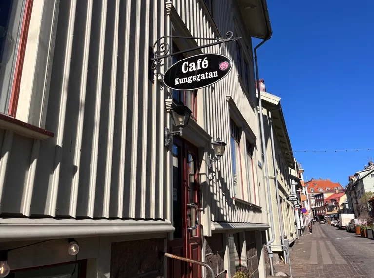 En caféskylt som hänger från sidan av en byggnad.