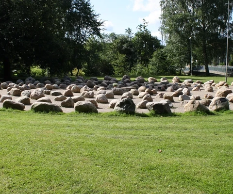 En stor grupp stenar som ligger på ett grönskande fält.