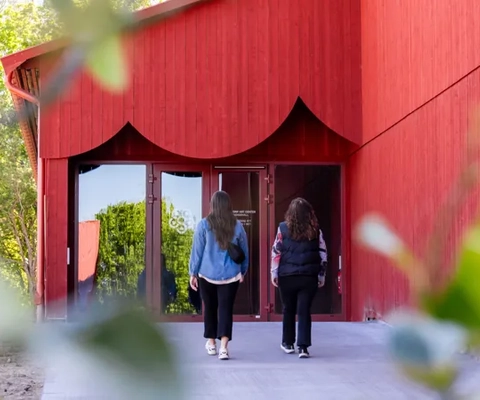 Några kvinnor går ut ur en röd byggnad.