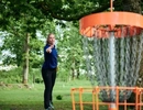 En kvinna kastar frisbee i en park.