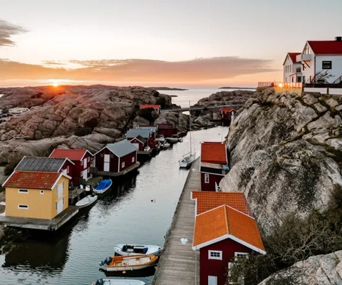 A group of small houses sitting on top of a cliff next to a body of water.