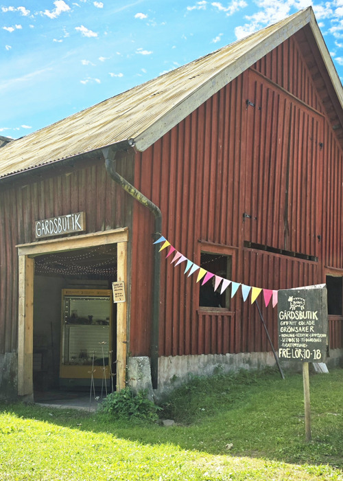 En röd ladugård med en skylt framför sig.