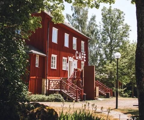 Rött hus bland gröna träd.