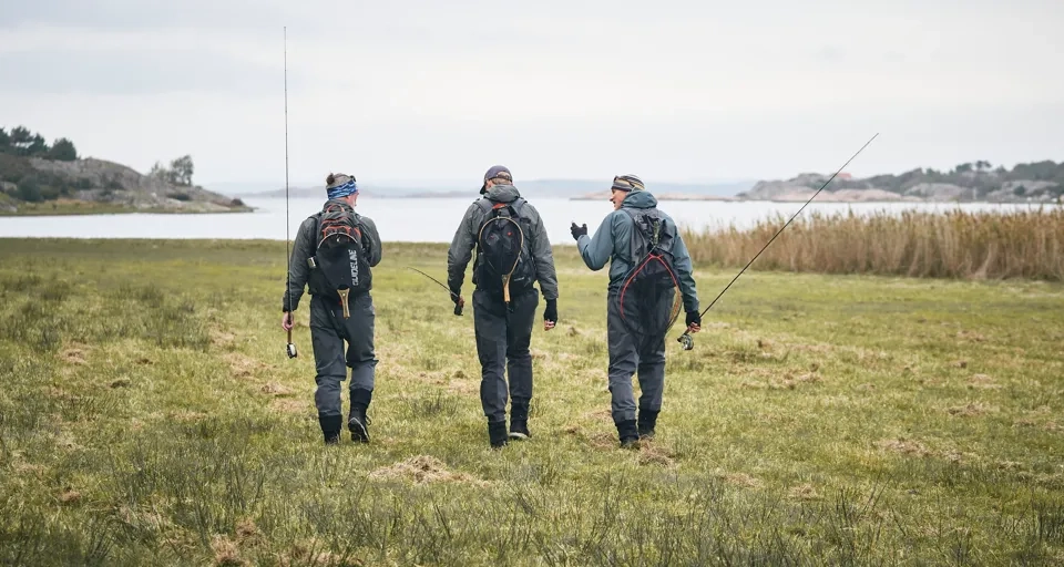 En grupp män som går över ett grönskande fält.