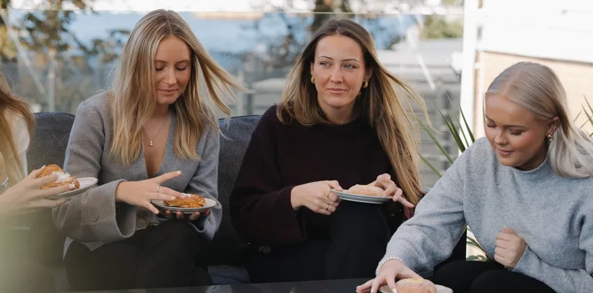 En grupp människor som sitter vid ett bord och fikar.