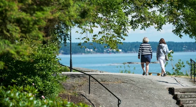 Två personer promenerar vid Vänerns vatten
