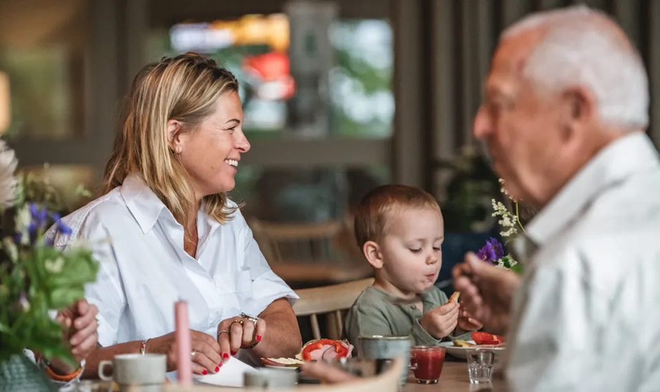 En grupp människor som sitter runt ett bord och äter mat.