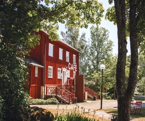 Rött hus bland gröna träd.