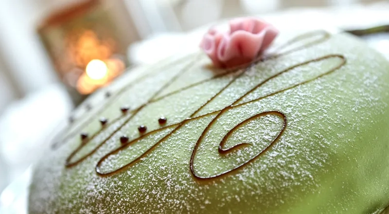 En grønn frostet kake med en rose på toppen.