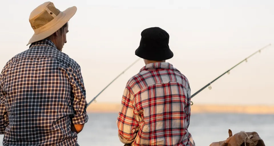 A couple of men sitting next to each other on a pier.