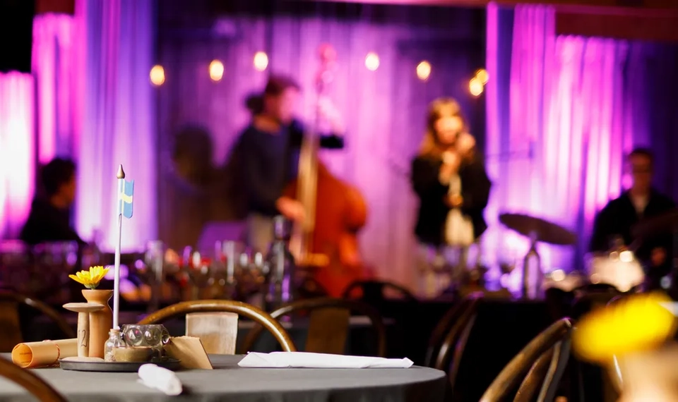 Musiklokal med scen och dukade bord.