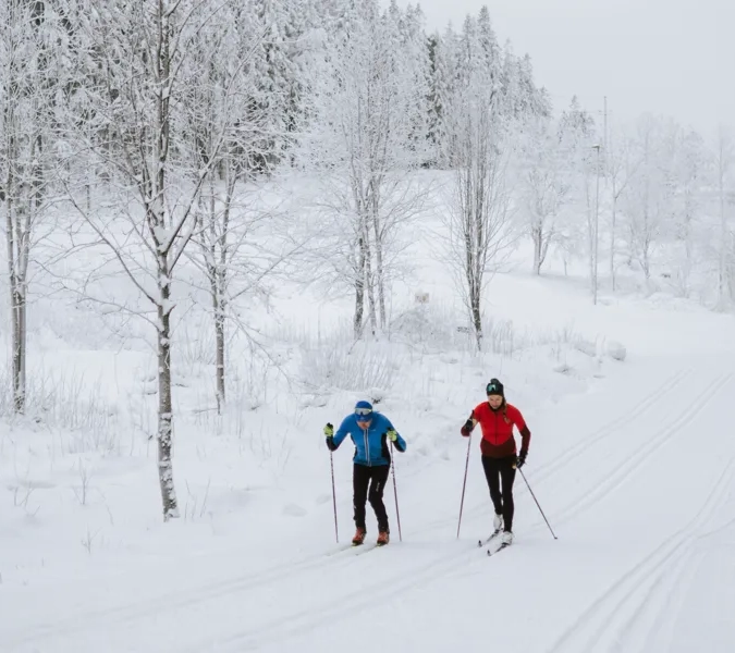 Två personer åker längdskidor i snön.