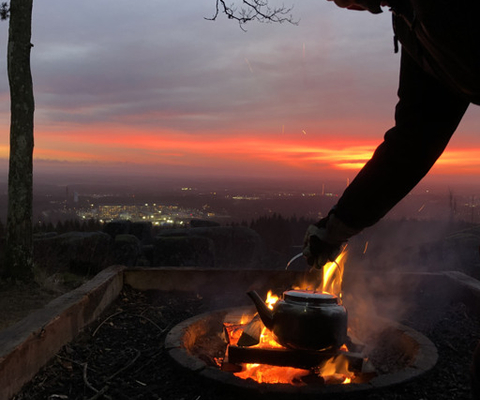 En person som lagar mat över en öppen eldstad.