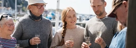 En grupp människor som står runt ett bord med glas.