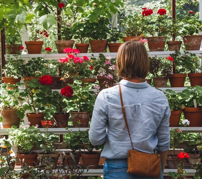 A woman standing in front of a wall of potted plants.