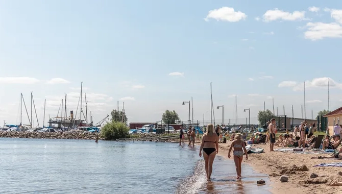 En grupp människor som går längs en strand intill Vättern.