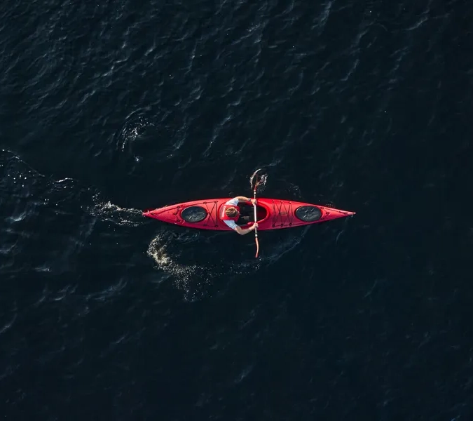 En person i en röd kajak mitt ute på en sjö.