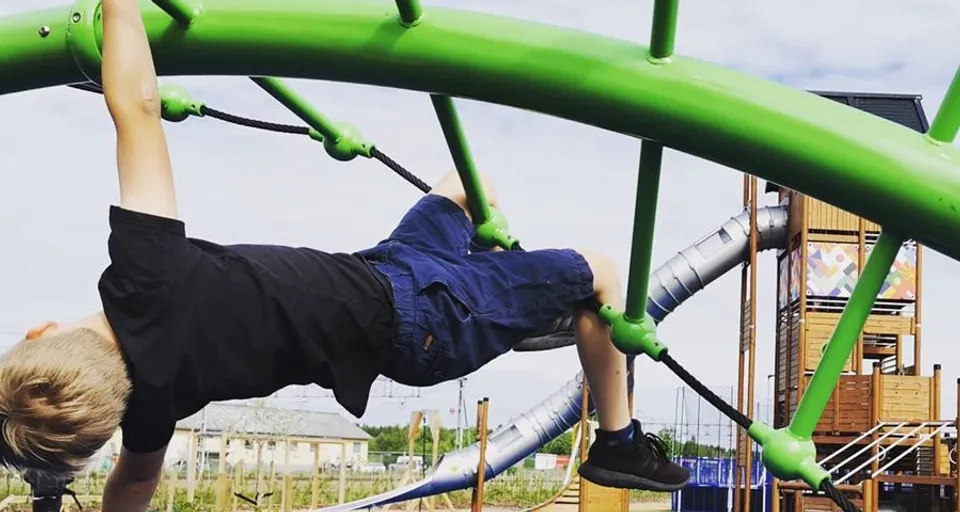 En ung pojke gör ett handstående på en lekplats.