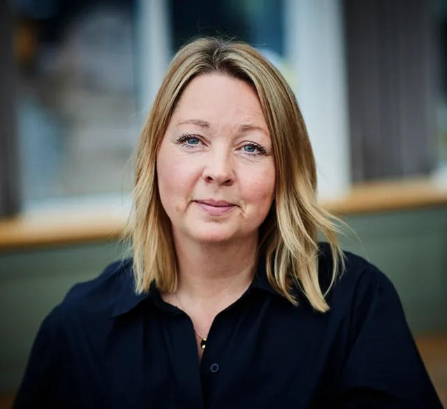 En kvinna med blont hår som bär en svart skjorta.