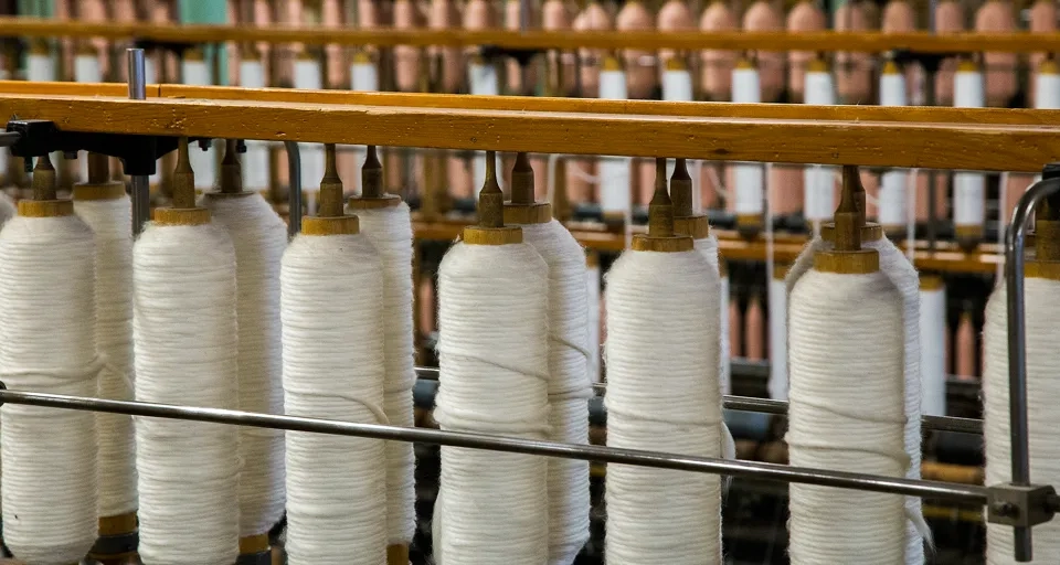Spinnspolar med vit tråd i en maskin på Rydals Museum