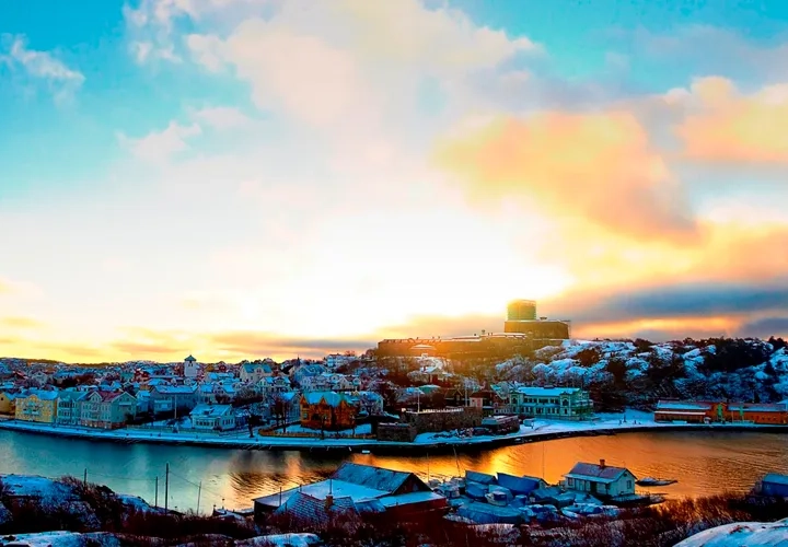 Solen går ner över en liten stad vid vattnet.