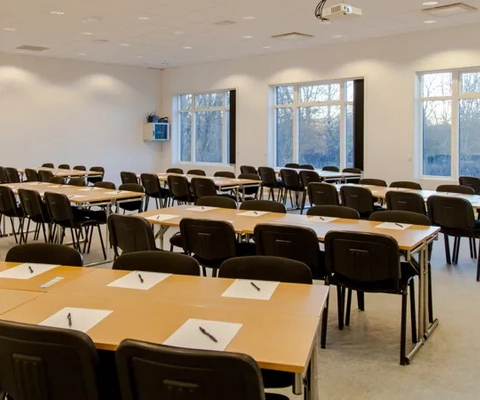 Ett konferensrum med bord, stolar och en projektorduk.