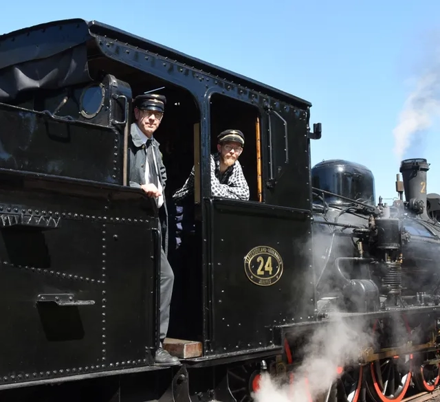 Två män står på ett gammalt ångtåg.