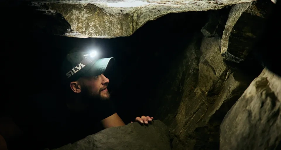 En man i en grotta med en ficklampa på huvudet.