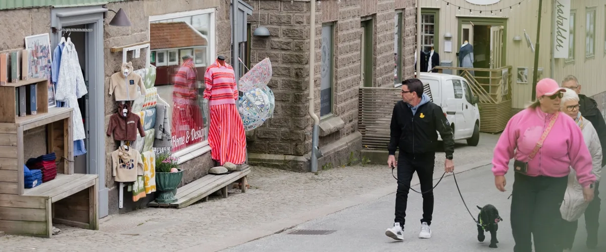 En kvinna går med en hund längs en gata.