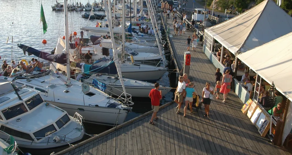 En grupp människor som står på en pir bredvid båtar.