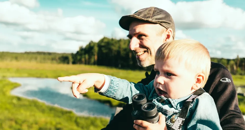 En man som håller ett barn och pekar på något.