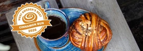 A blue plate topped with a pastry next to a cup of coffee.