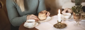 Kvinna fikar på kanelbulle och kaffe