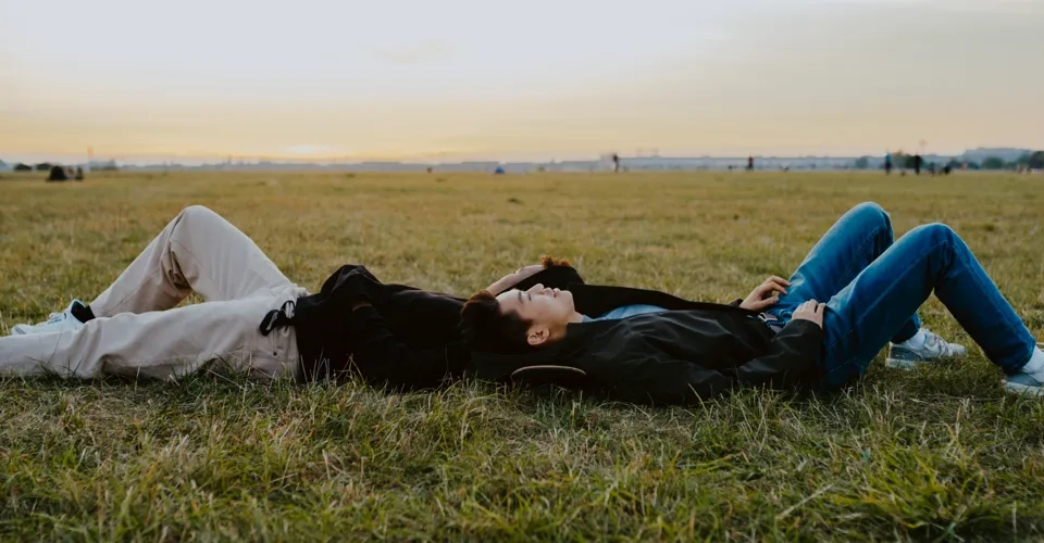 Två personer ligger i gräset och tittar upp mot himlen