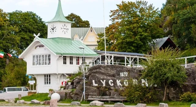 En vit byggnad med ett grönt tak intill ett vattendrag.