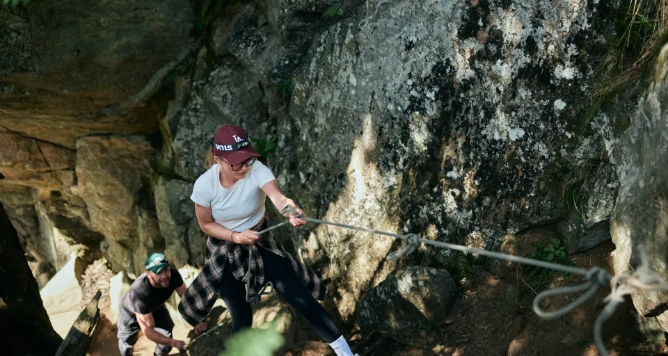 En kvinna drar i ett rep på en klippa.