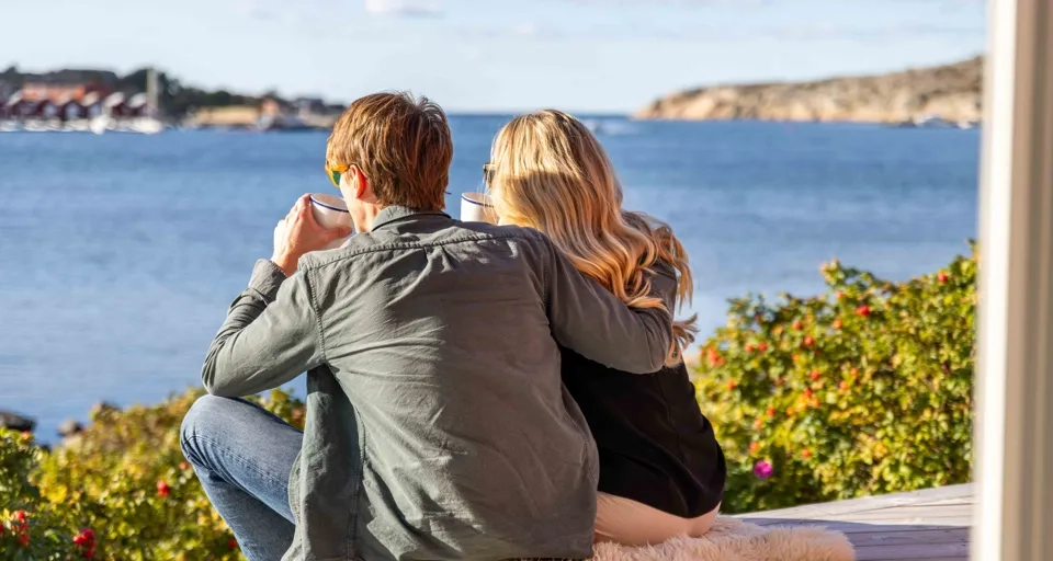 Ett ungt par fikar på terrasen med en underbar  skärgårdsvy hos Hönö Sjöbodar