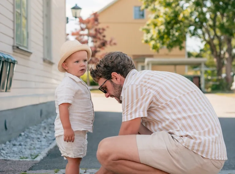 En man knäböjer bredvid en liten pojke.