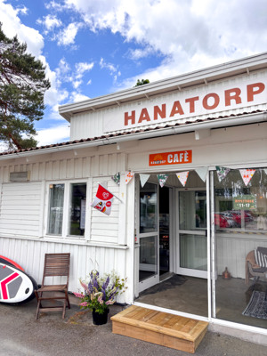En vit byggnad med en skylt och en surfbräda framför sig.