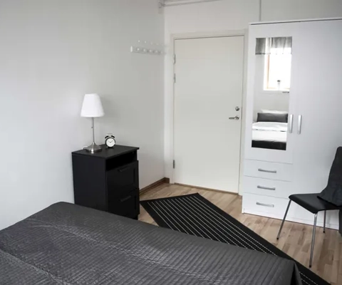 Ett svartvitt sovrum med en säng och en stol.