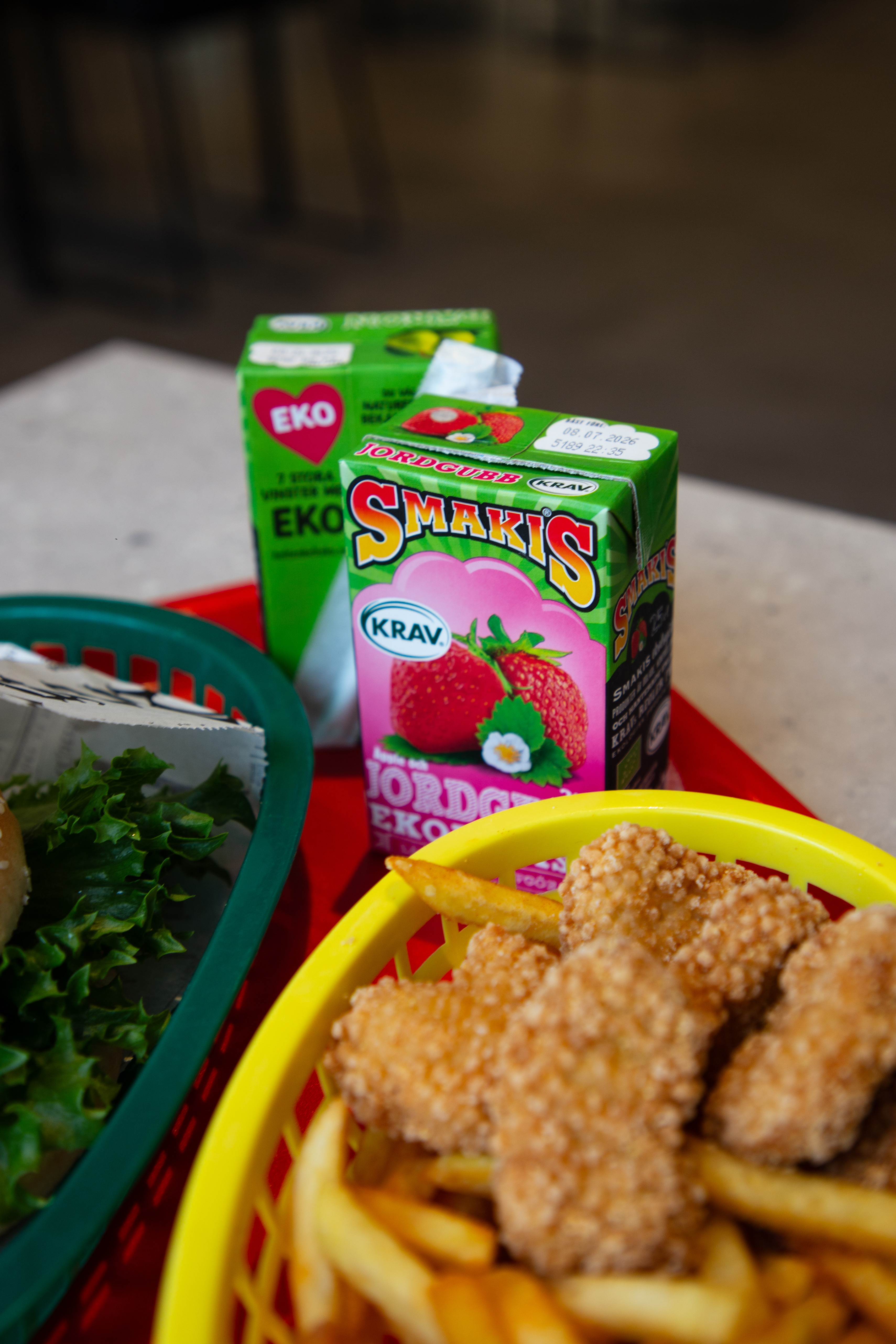 En röd bricka fylld med mat bredvid en smakis dryck.