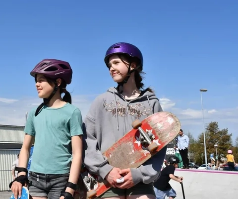 Några barn som står bredvid varandra och håller i skateboards.